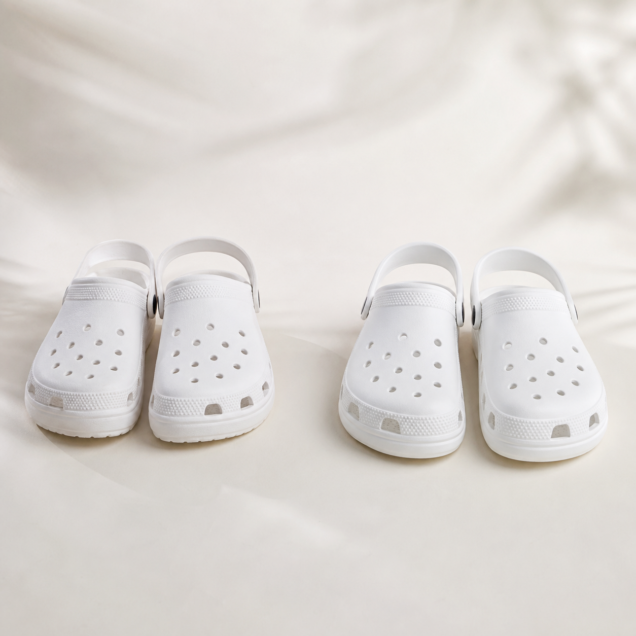 White Crocs-style camp clogs on a warm studio background